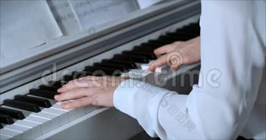女或女学生或职业钢琴家在一架漂亮的白色钢琴上演奏古典音乐，钢琴家的手